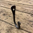 side view of a hand forged iron hook on a wooden floor
