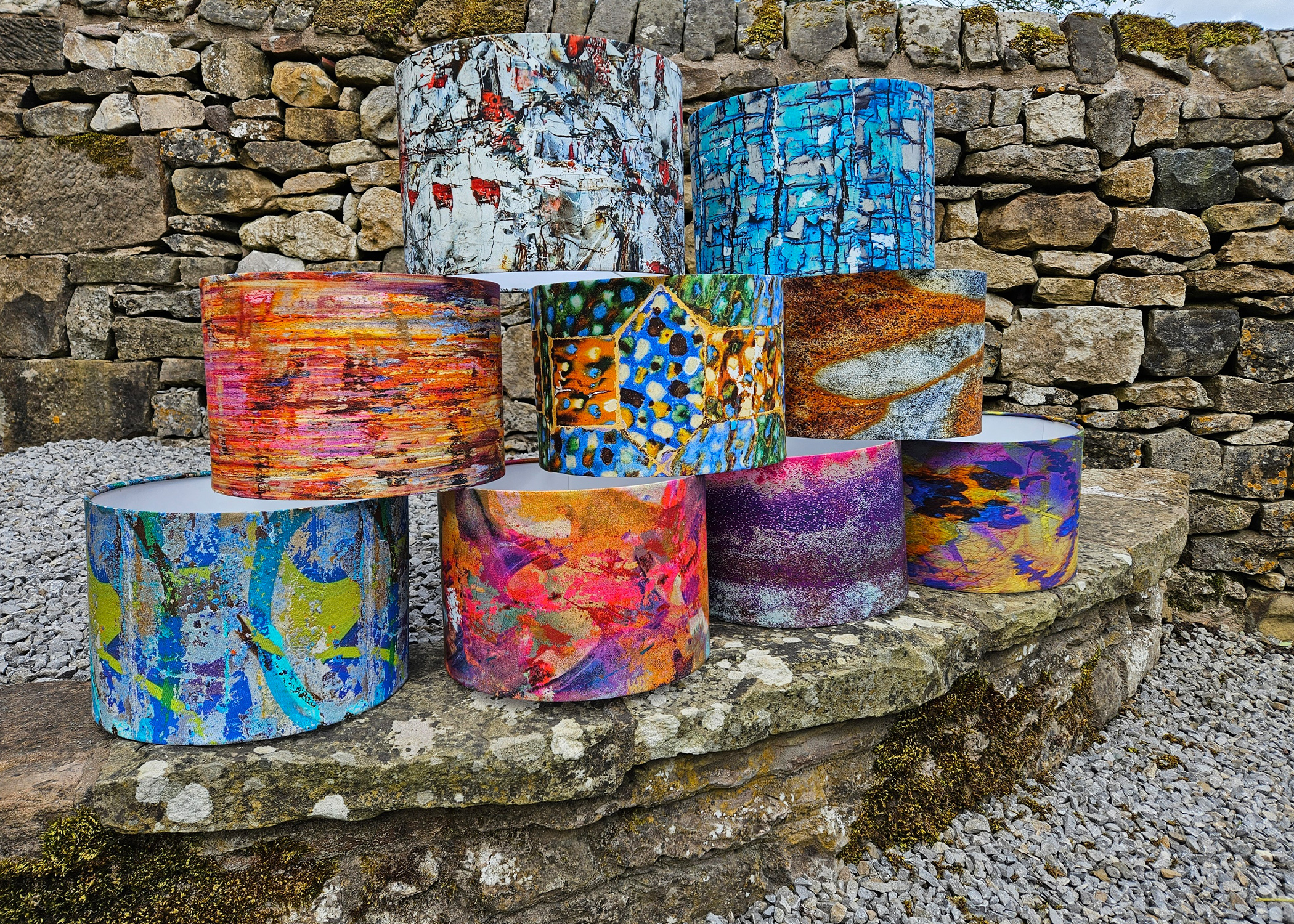 Colourful lampshades on a stone wall.